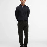 Vue en pied du style avec le polo noir manches longues Barbour, un pantalon en velours côtelé foncé et des mocassins