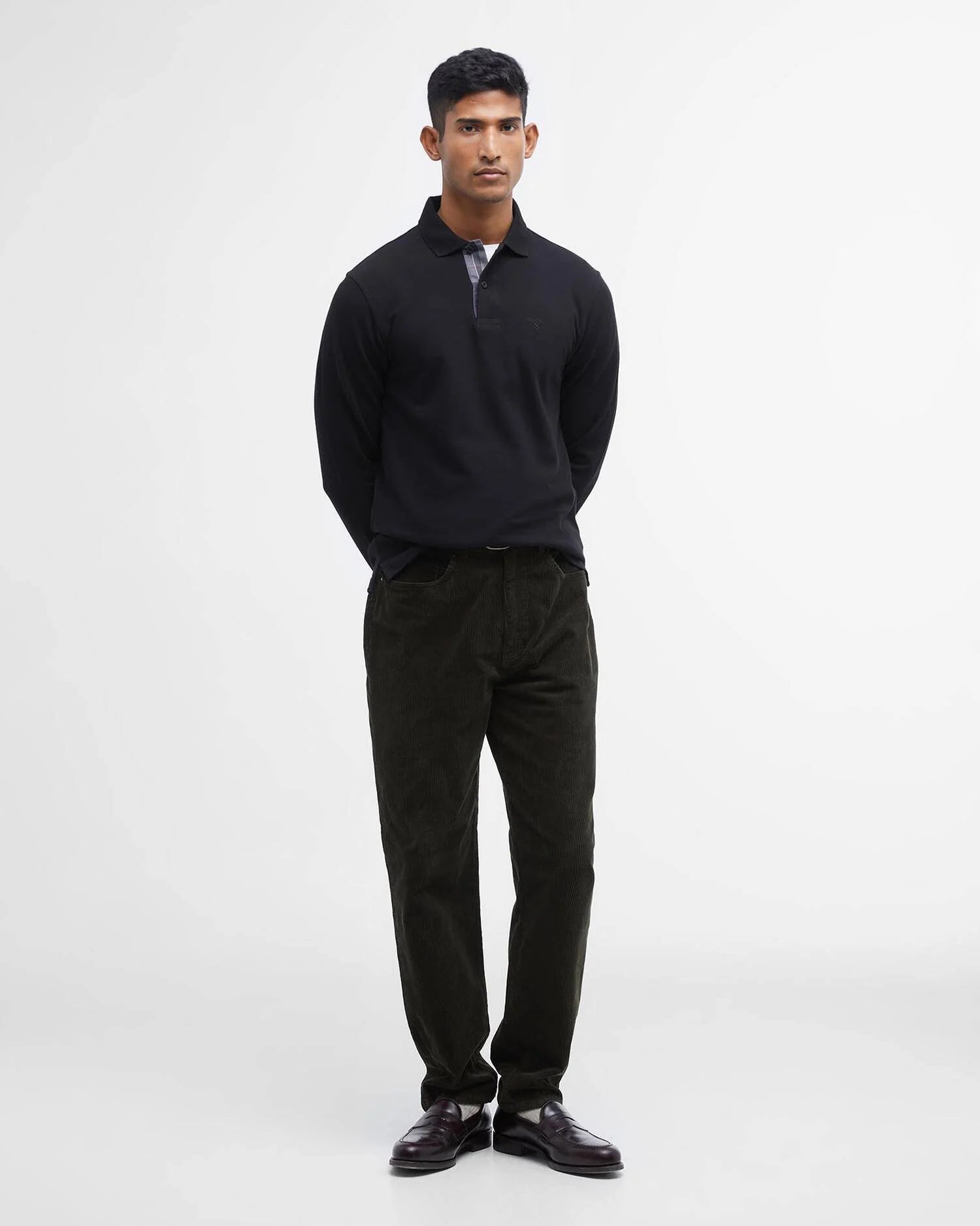 Vue en pied du style avec le polo noir manches longues Barbour, un pantalon en velours côtelé foncé et des mocassins
