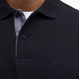 Gros plan sur le col du polo Essentiel noir Barbour, la doublure tartan et le logo brodé sur la poitrine