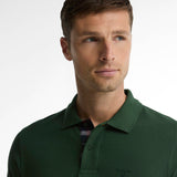 Gros plan du buste montrant la patte boutonnée tartan du polo vert foncé Barbour