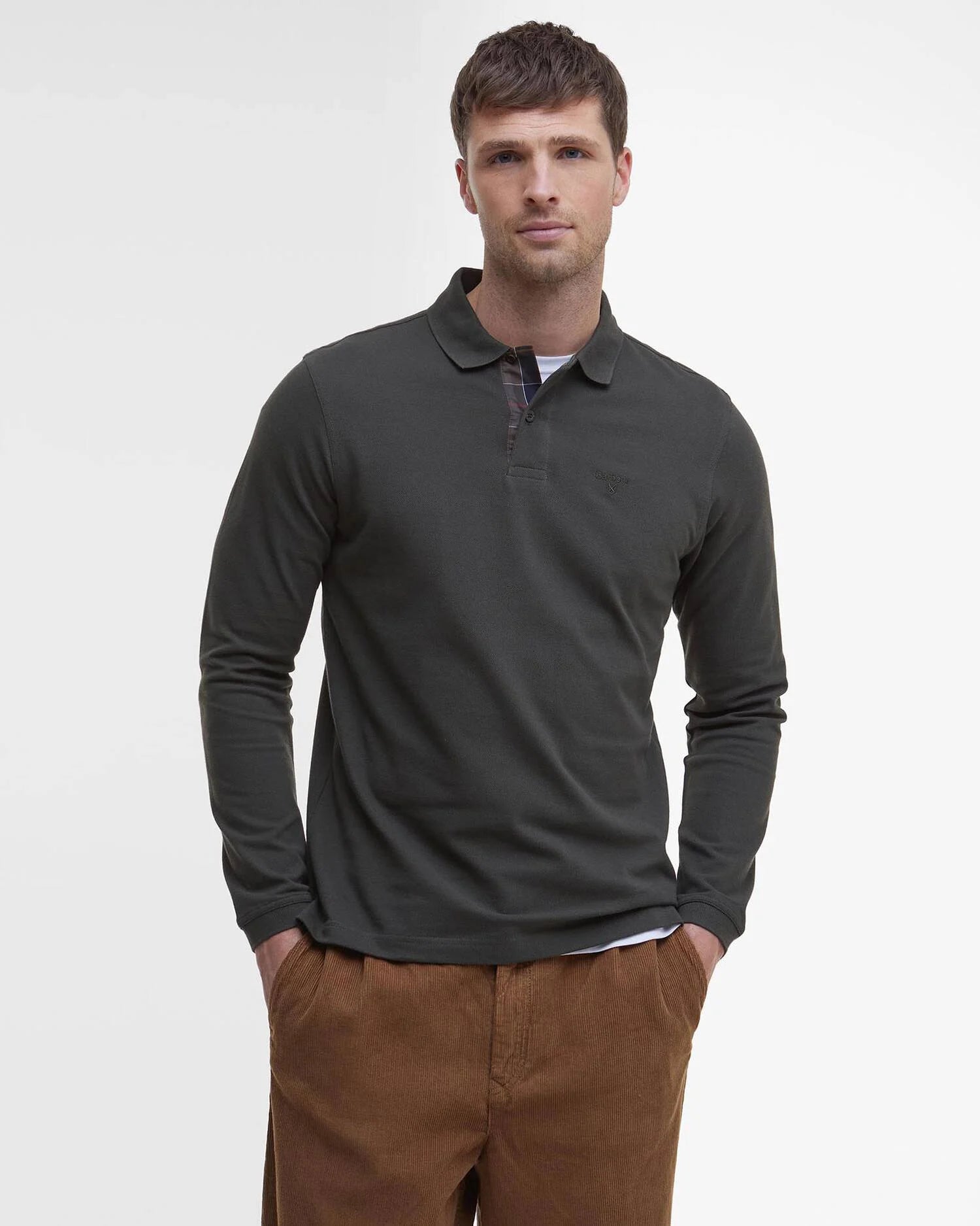 Mannequin portant le polo manches longues Essentiel vert forêt BARBOUR HOMME avec les mains dans les poches
