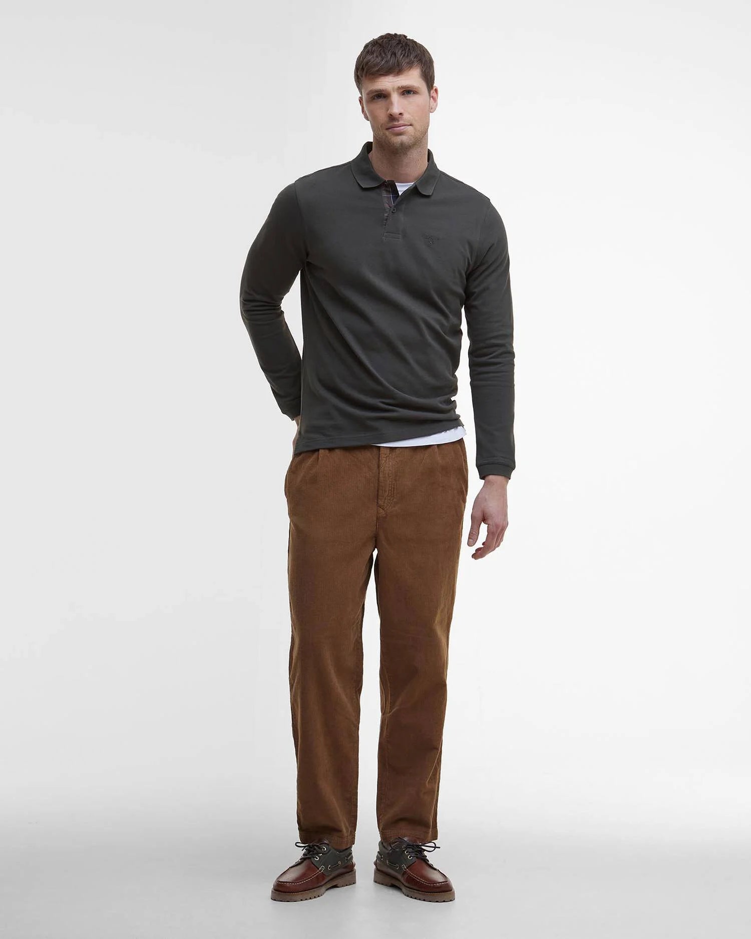Vue d'ensemble du look mannequin avec polo vert forêt Barbour, pantalon en velours côtelé marron et chaussures en cuir
