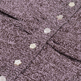Gros plan sur la maille chinée et les boutons fantaisie en forme d'étoile et de cœur du pull Tilda
