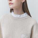 Gros plan sur la collerette plissée blanche et le logo brodé sur la poche du pull SUNCOO FEMME Pacoli