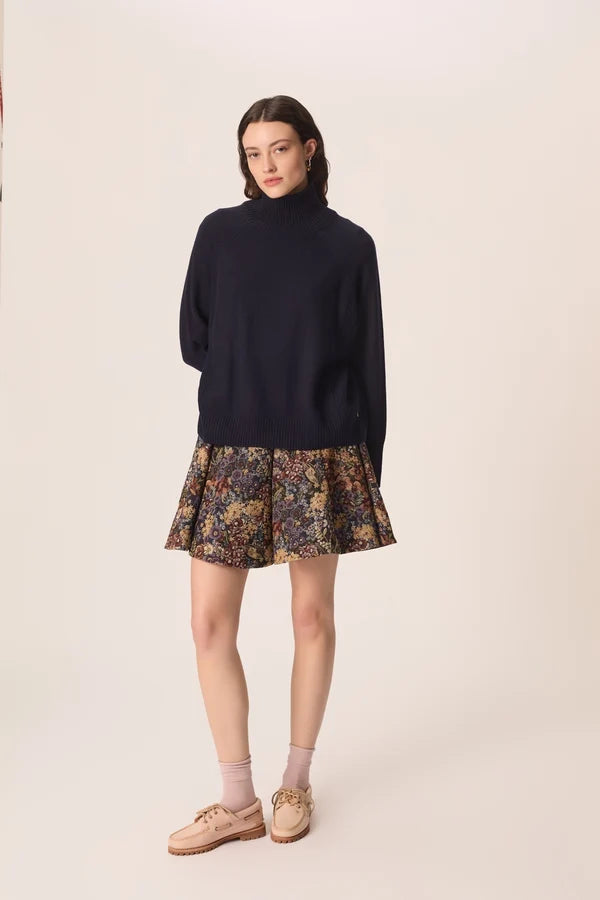 Vue d ensemble du pull col roulé marine Aramis DES PETITS HAUTS porté avec une jupe courte imprimée