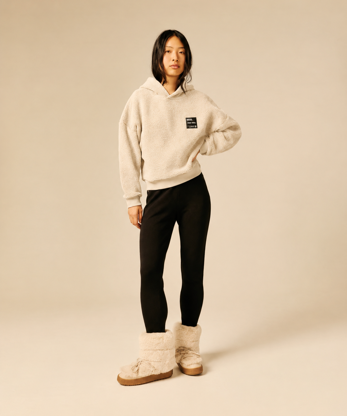 Sweat à capuche beige clair en maille sherpa SUN VALLEY FEMME Deltry porté de face avec un legging noir et des boots fourrées