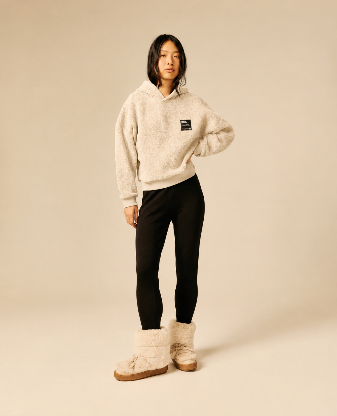 Sweat à capuche beige clair en maille sherpa SUN VALLEY FEMME Deltry porté de face avec un legging noir et des boots fourrées