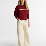 Vue d'ensemble du look avec le sweat rouge canneberge Barbour, un jean beige large et des chaussures en cuir