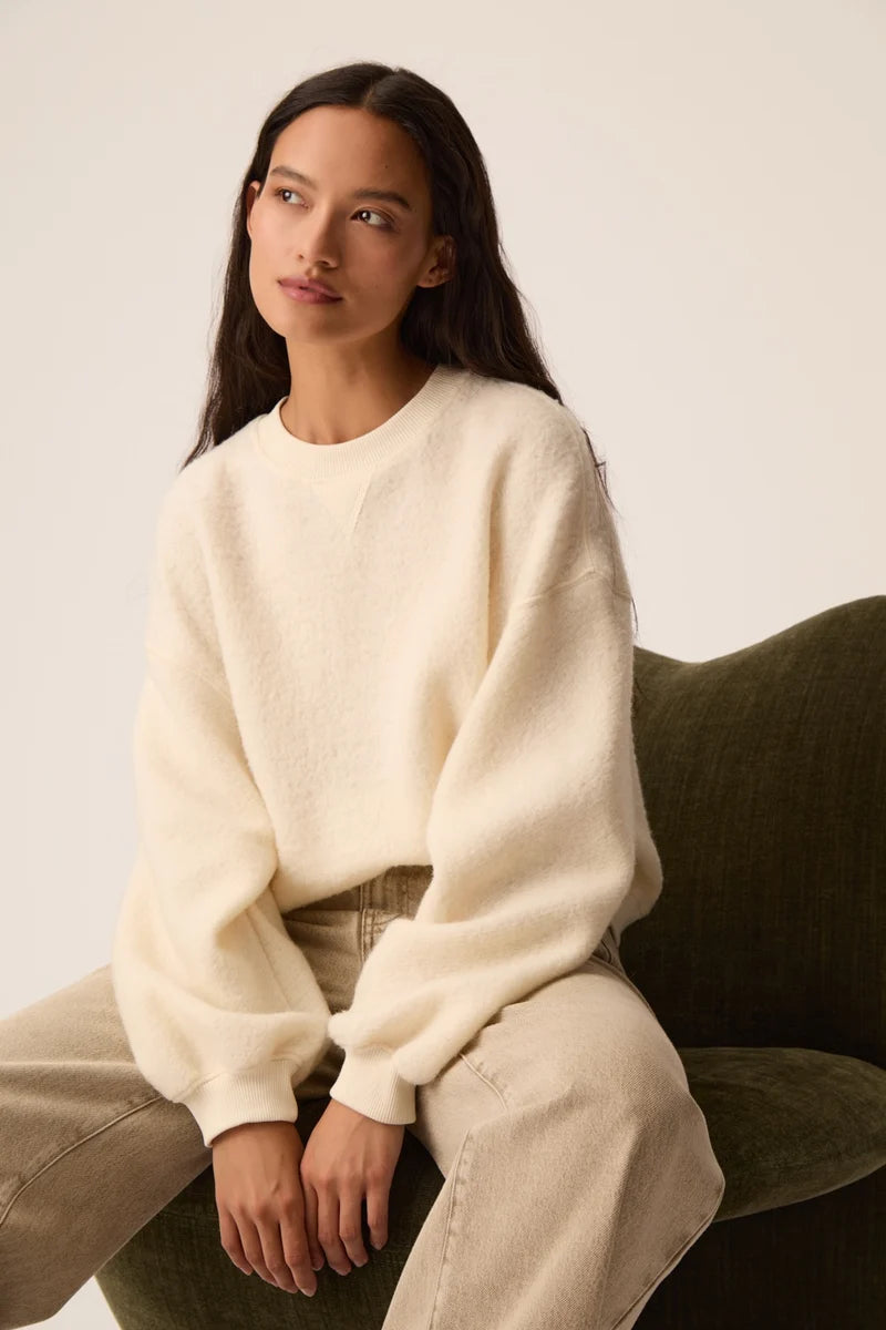 Modèle assis portant le sweat en molleton bouclette crème Jonas DES PETITS HAUTS