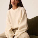 Modèle assis portant le sweat en molleton bouclette crème Jonas DES PETITS HAUTS