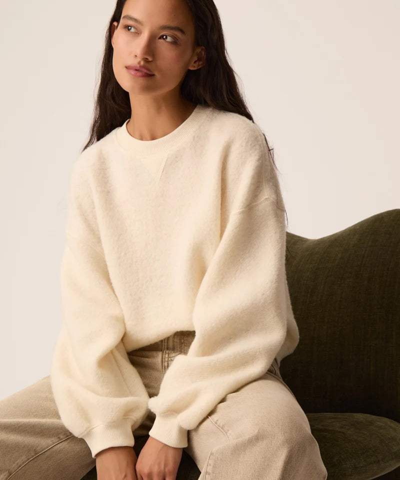 Modèle assis portant le sweat en molleton bouclette crème Jonas DES PETITS HAUTS