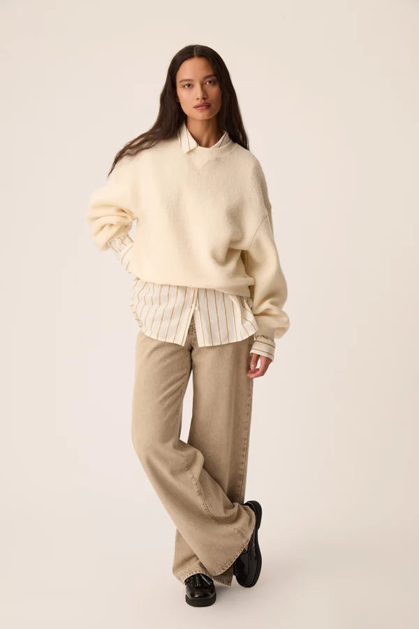 Vue de face du sweat oversize crème Jonas DES PETITS HAUTS avec un pantalon large et une chemise rayée 