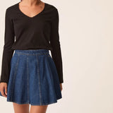 Modèle portant le t-shirt manches longues noir Izolène DES PETITS HAUTS avec une jupe en jean évasée