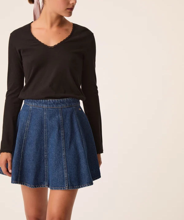 Modèle portant le t-shirt manches longues noir Izolène DES PETITS HAUTS avec une jupe en jean évasée
