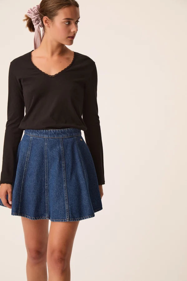 Modèle portant le t-shirt manches longues noir Izolène DES PETITS HAUTS avec une jupe en jean évasée