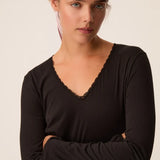 Zoom sur le décolleté en V bordé de dentelle du t-shirt noir Izolène DES PETITS HAUTS
