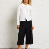 Silhouette complète modèle avec le top écru Zea DES PETITS HAUTS, pantalon large noir et derbies