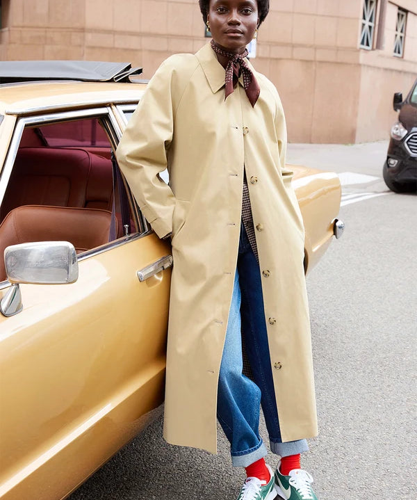Modèle portant le trench long beige Yvette DES PETITS HAUTS avec un jean et un foulard