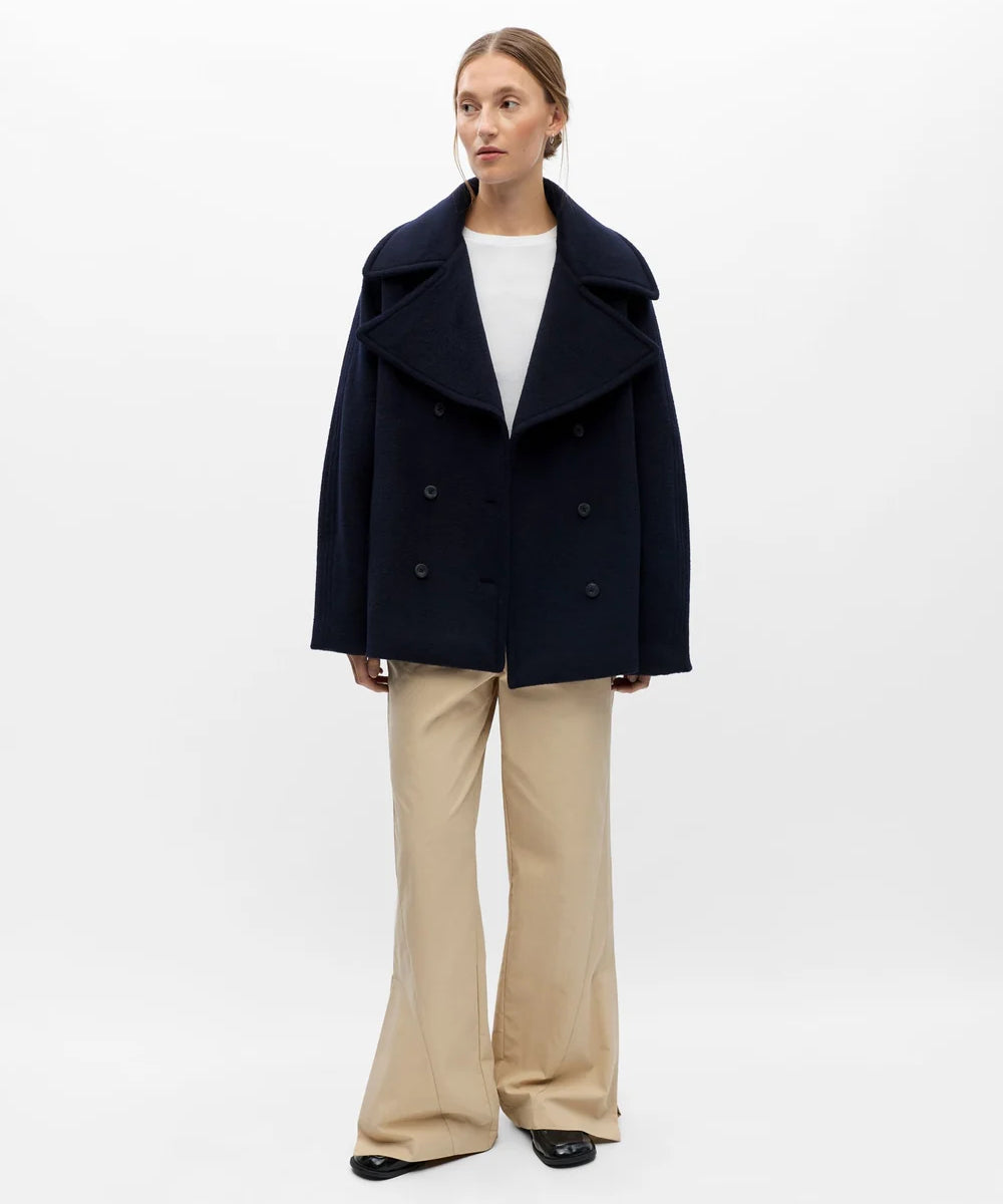Vue d'ensemble de la veste courte marine OBJECT Objeaco portée avec un pantalon fluide beige