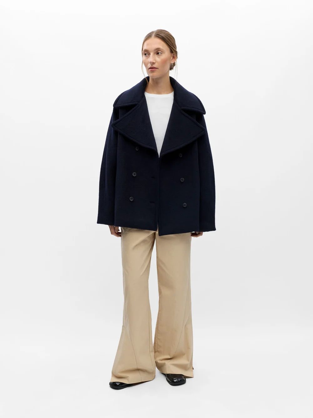 Vue d'ensemble de la veste courte marine OBJECT Objeaco portée avec un pantalon fluide beige