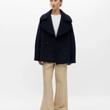 Vue d'ensemble de la veste courte marine OBJECT Objeaco portée avec un pantalon fluide beige