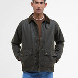Mannequin portant la veste ciree courte Bedale vert fougere BARBOUR HOMME fermee sur un pull brun