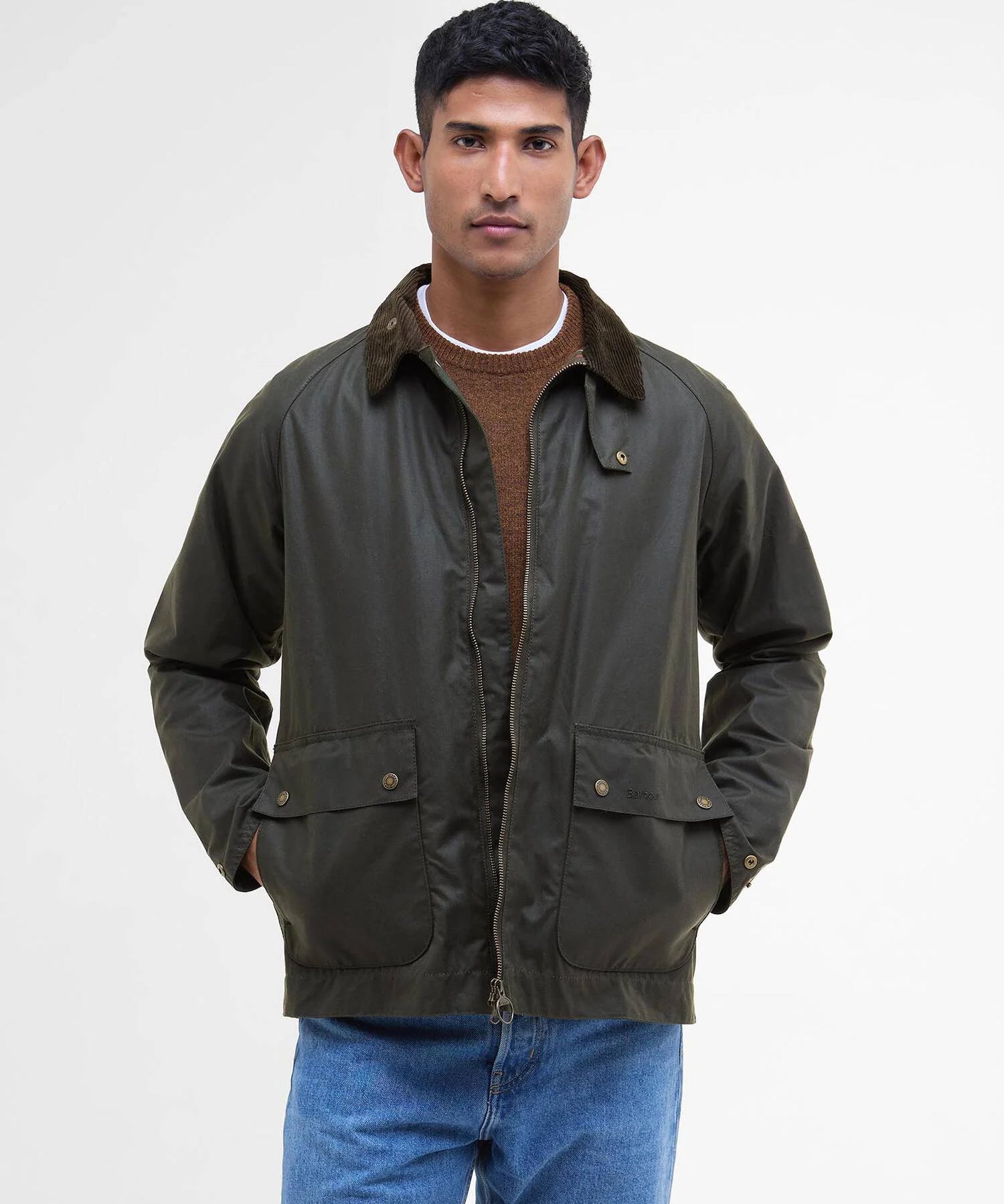 Mannequin portant la veste ciree courte Bedale vert fougere BARBOUR HOMME fermee sur un pull brun