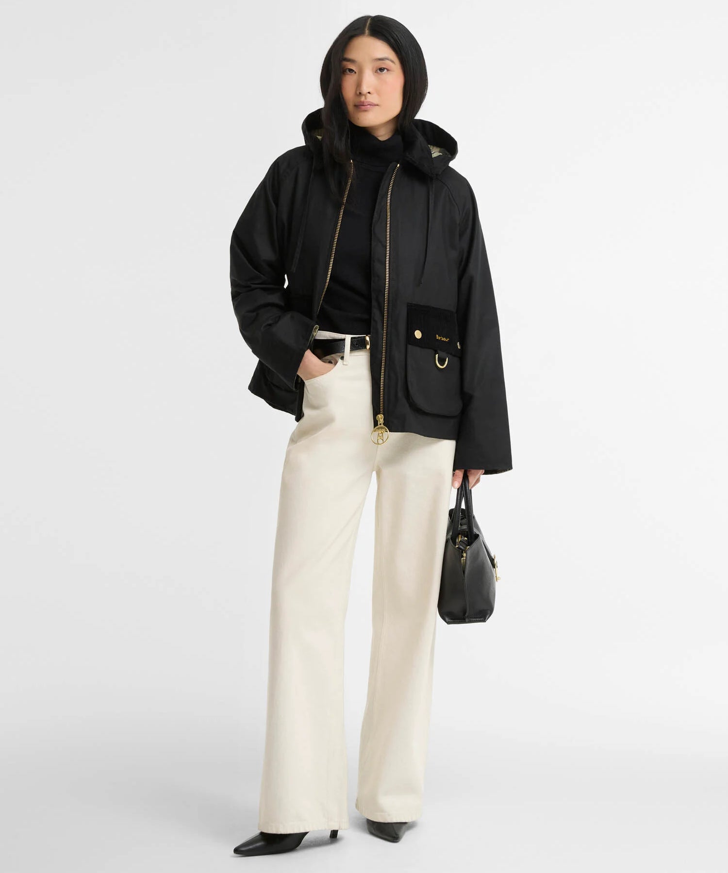 Look complet avec la veste cirée Carville noire Barbour, un pantalon écru et des bottines noires