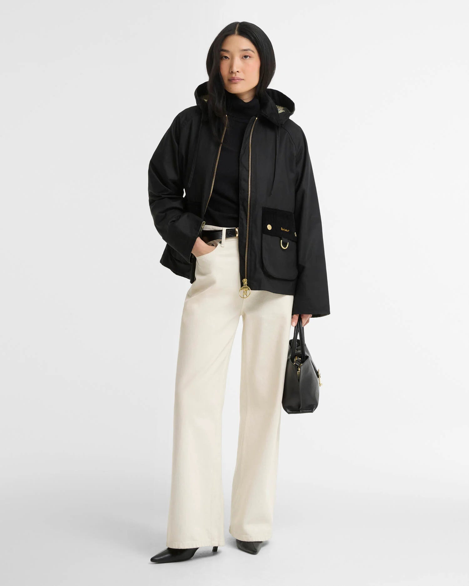 Look complet avec la veste cirée Carville noire Barbour, un pantalon écru et des bottines noires