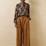 Vue en pied du mannequin portant la blouse fluide Getanoa bleu encre et pantalon large marron