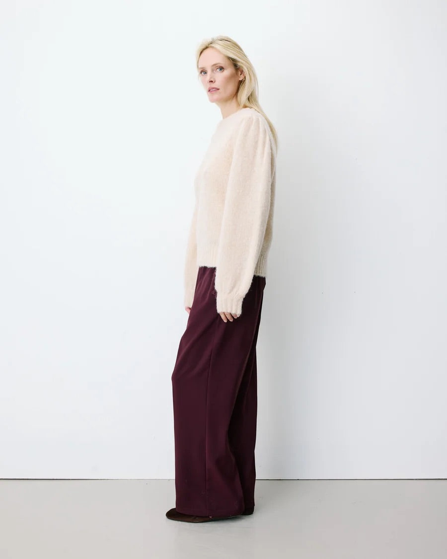 Pull ANTOINE GRACE & MILA beige – porté de profil avec pantalon large bordeaux